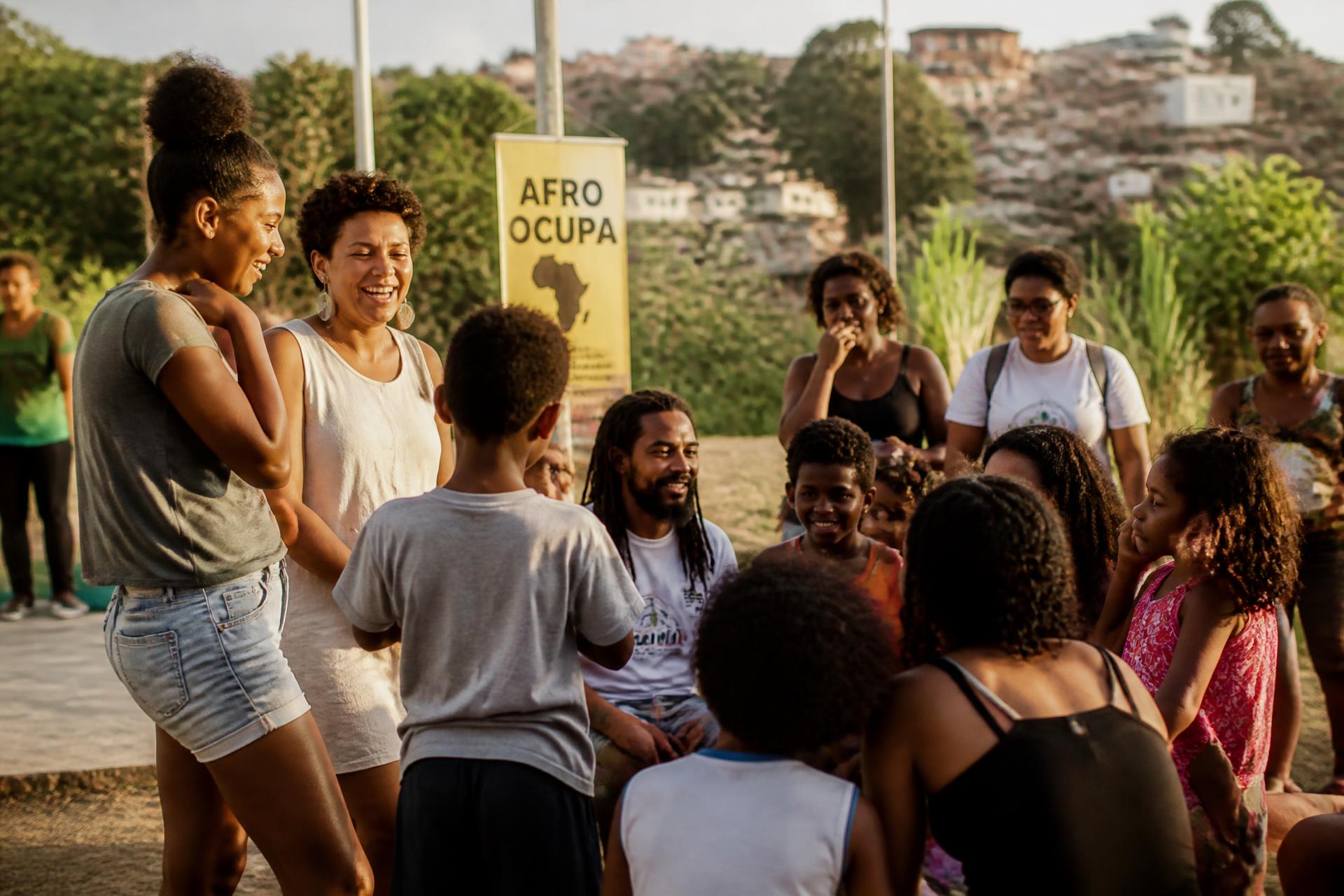 Encontro comunitário ao entardecer em Salvador, com adultos e crianças reunidos em roda